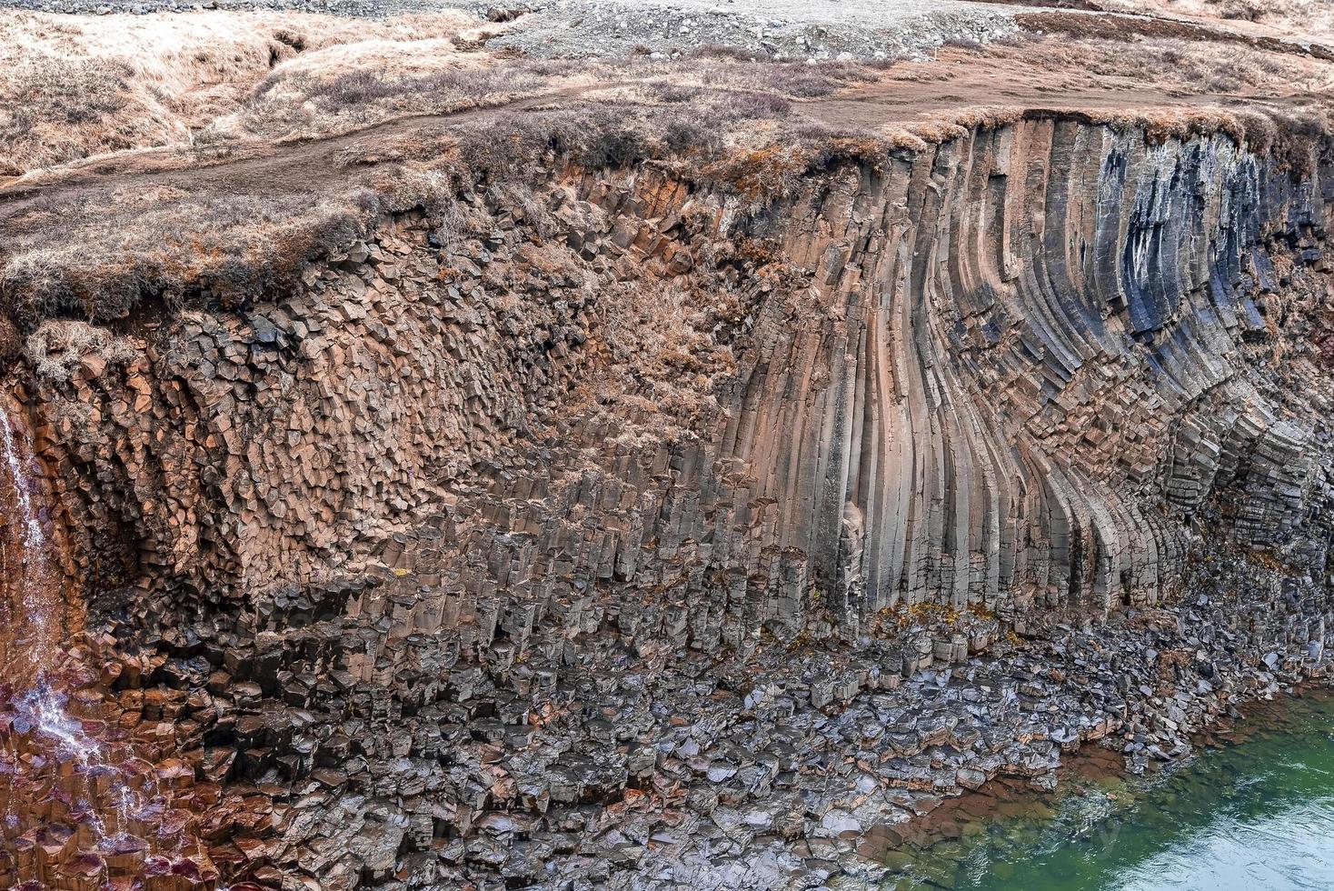 Scenic view of basalt column formation by Litlanesfoss waterfall in valley photo