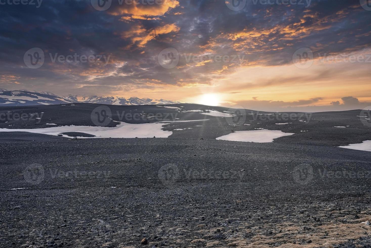 Scenic view of sun shining over snow on volcanic landscape during sunset photo