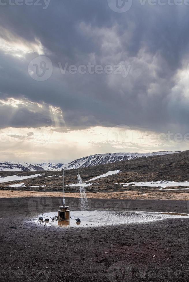 Outdoor hot shower station from geothermal power at Krafla against cloudscape photo