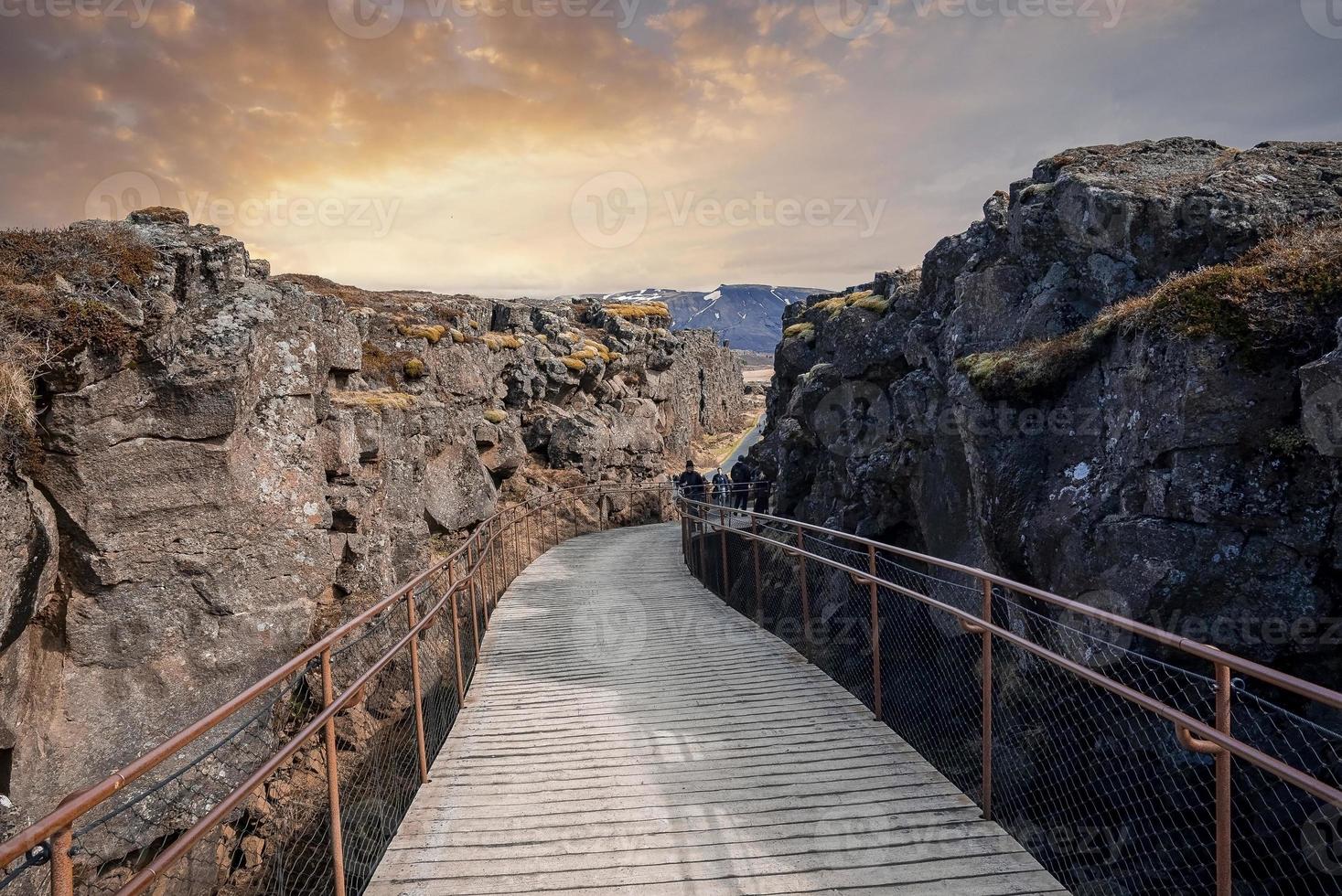 Tourists walking on bridge amidst rock formations at  Thingvellir national park photo