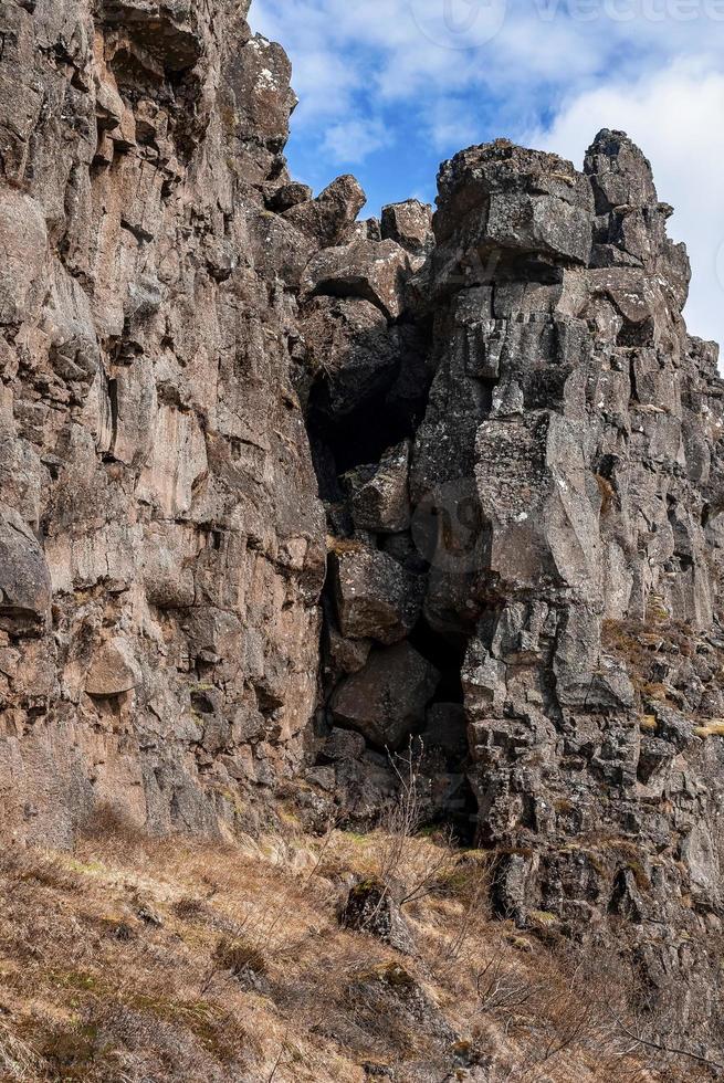 Low angle view of rock formations on majestic cliff against cloudy sky photo