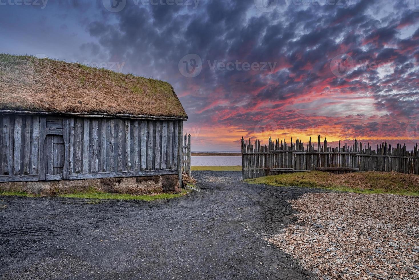 Wooden traditional house surrounded by fence against dramatic sky during sunset photo