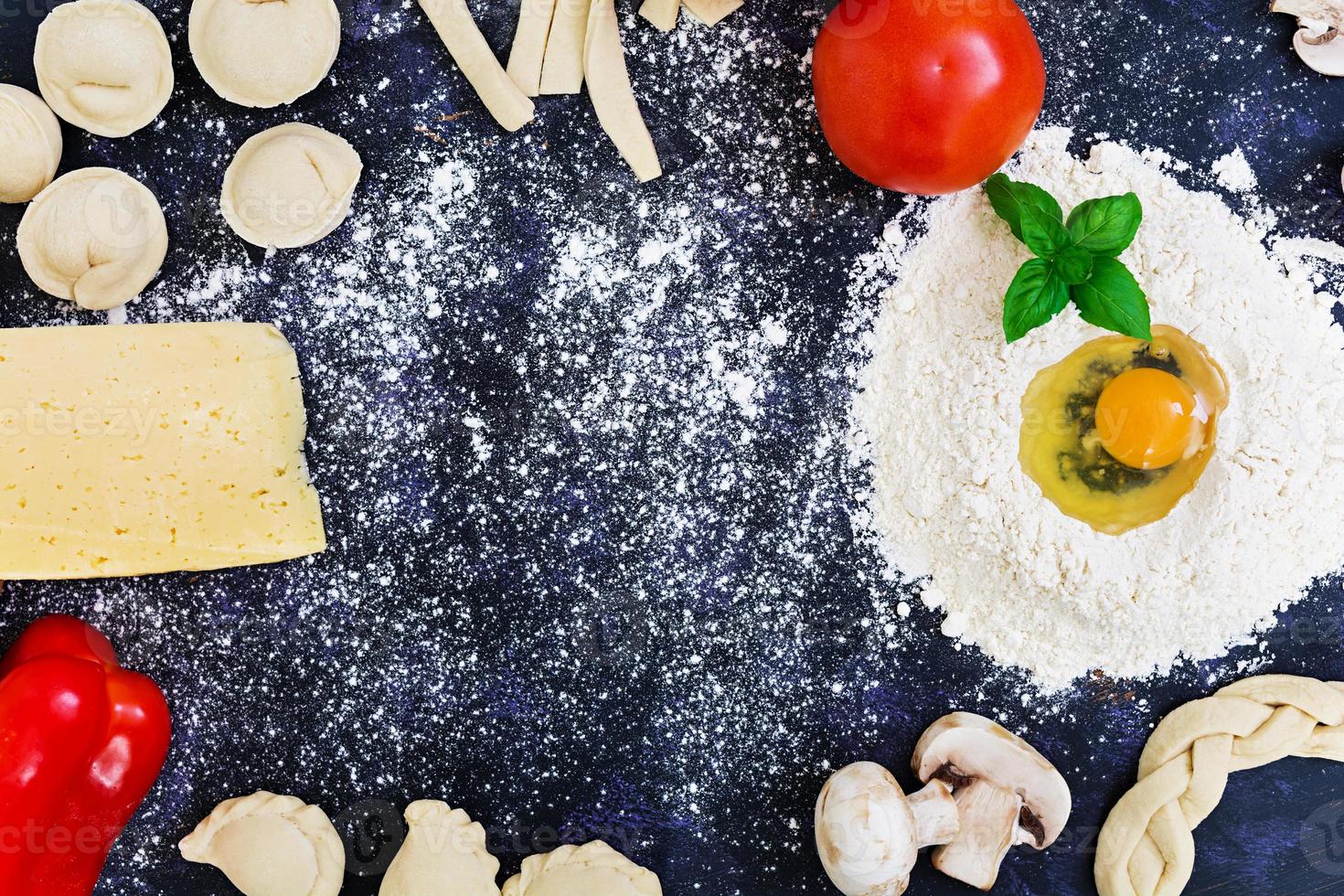 Raw pizza dough with ingredients and spices on dark background. Top view photo