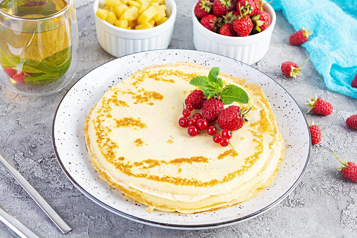 Pancakes with caramelized apples, raspberries, strawberries and red currants. Brunch with green tea and crepes. photo