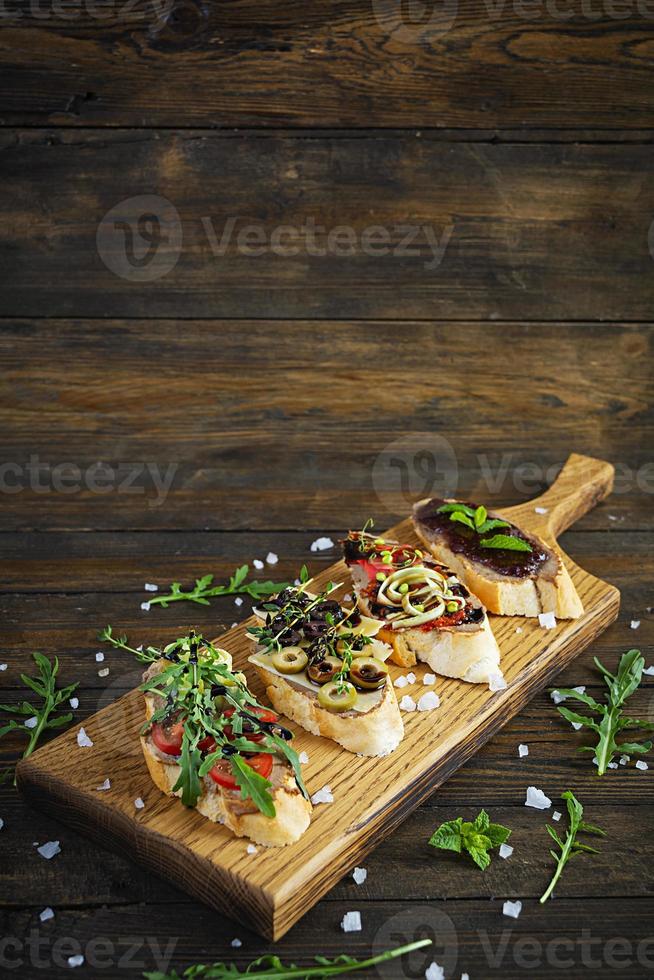 Bruschetta with chicken liver paste. Delicious bruschettas with various fillings. Different bruschetta ob wooden background photo