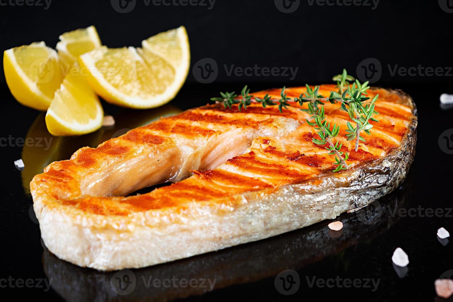 pescado salmón a la parrilla en tablero de piedra. salmón atlántico a la sal frito a la parrilla con limón foto