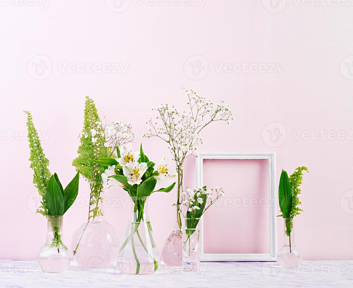 Flowers and plants in flask with frame. Beautiful spring background with flowers in vase. photo