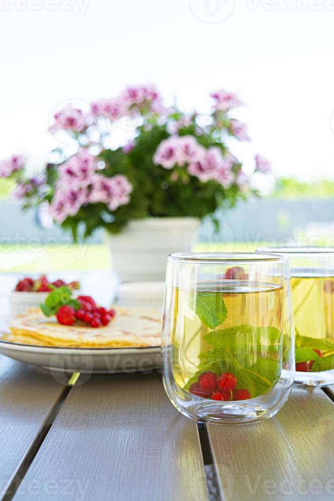 Pancakes with caramelized apples, raspberries, strawberries and red currants. Brunch with green tea and crepes. photo