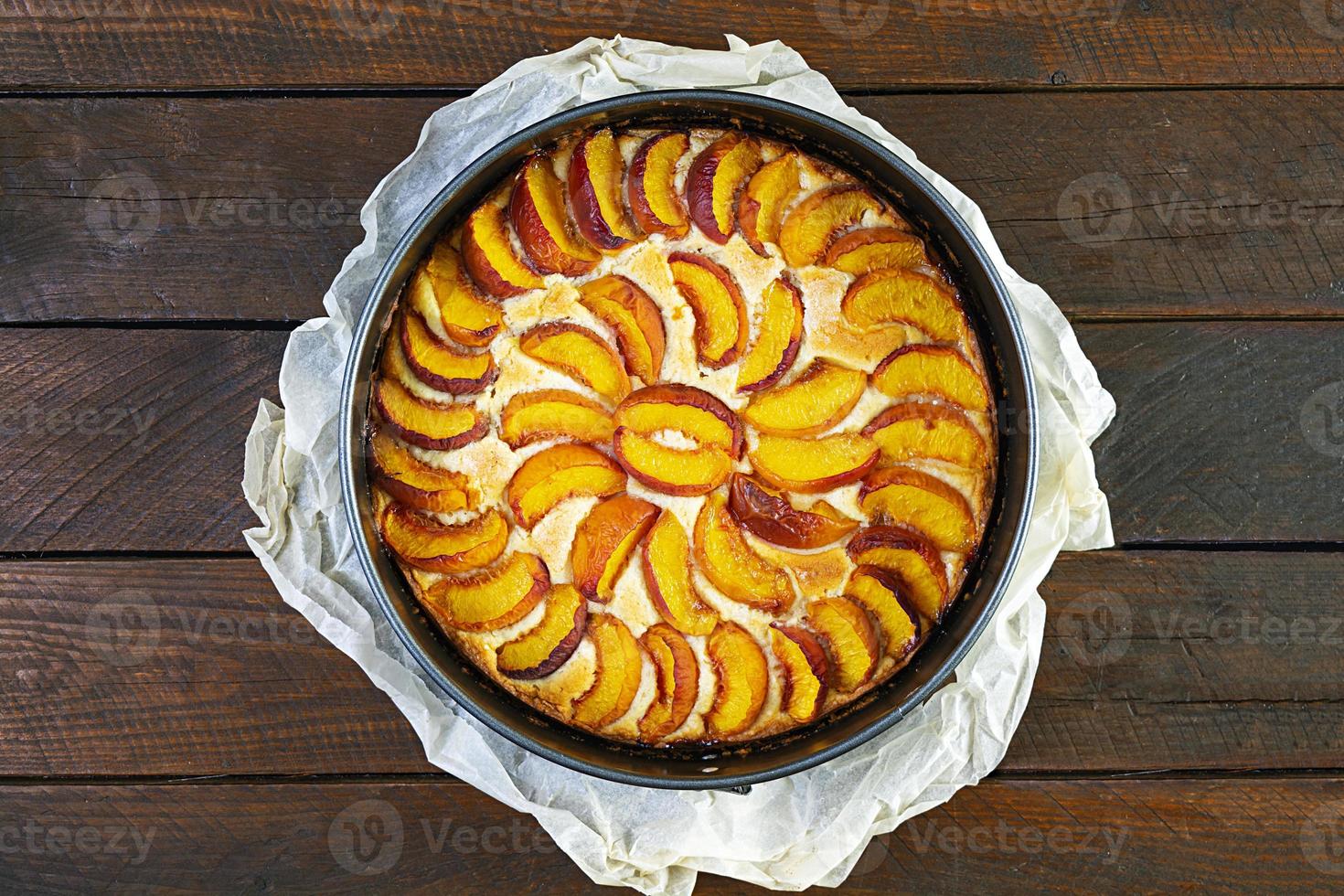 Delicious homemade peach pie on wooden background. Top view photo