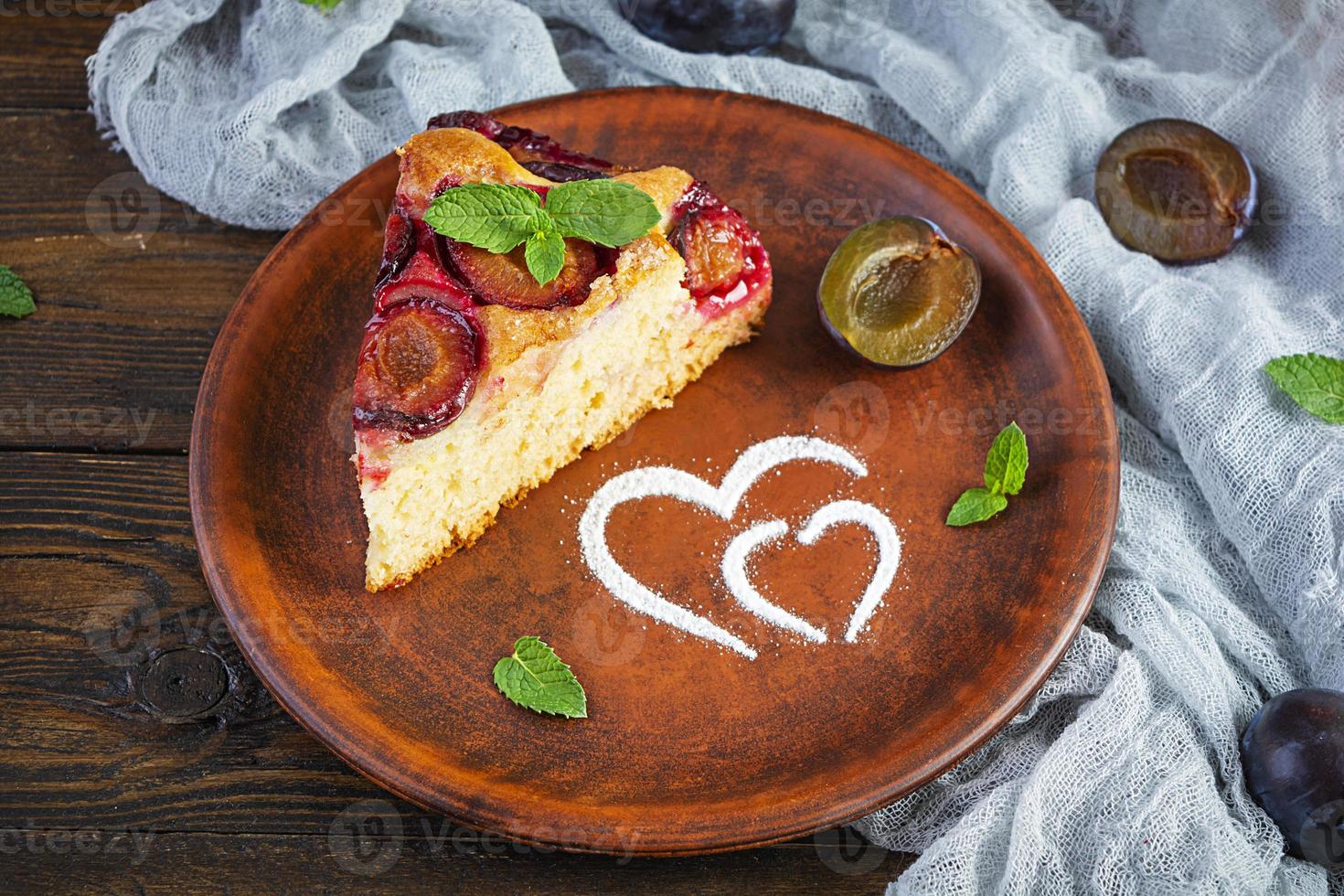Delicious homemade plum pie on wooden background photo