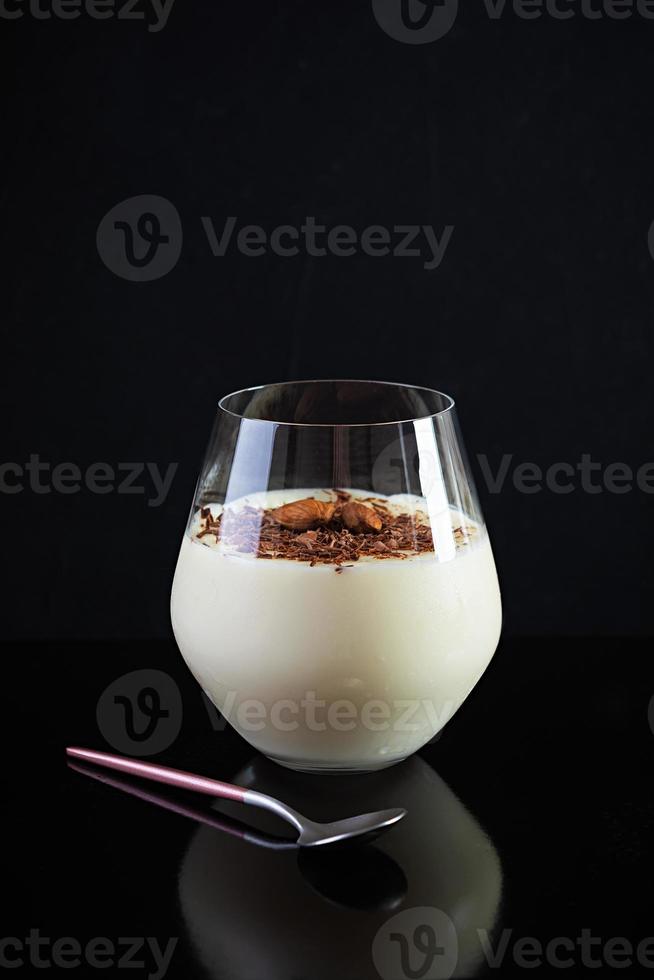 Sweet milk pudding with almonds and chocolate chips isolated on dark background photo