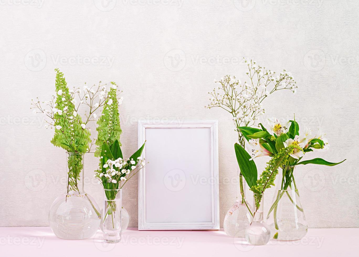 Flowers and plants in flask with frame. Beautiful spring background with flowers in vase. photo