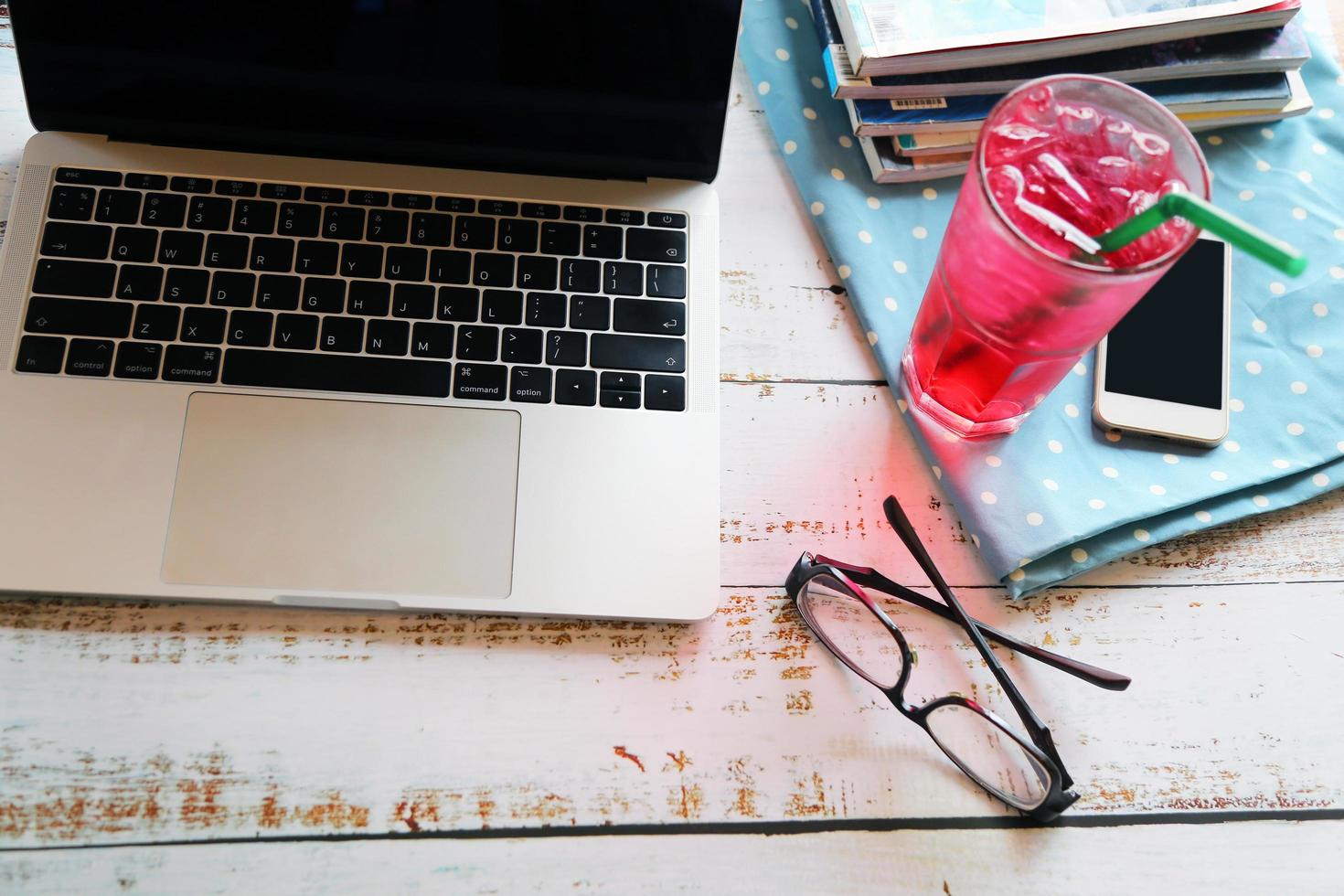 Laptop with glasses, smartphone, a glass of cold drink and magazine on wooden table, Working remotely. photo