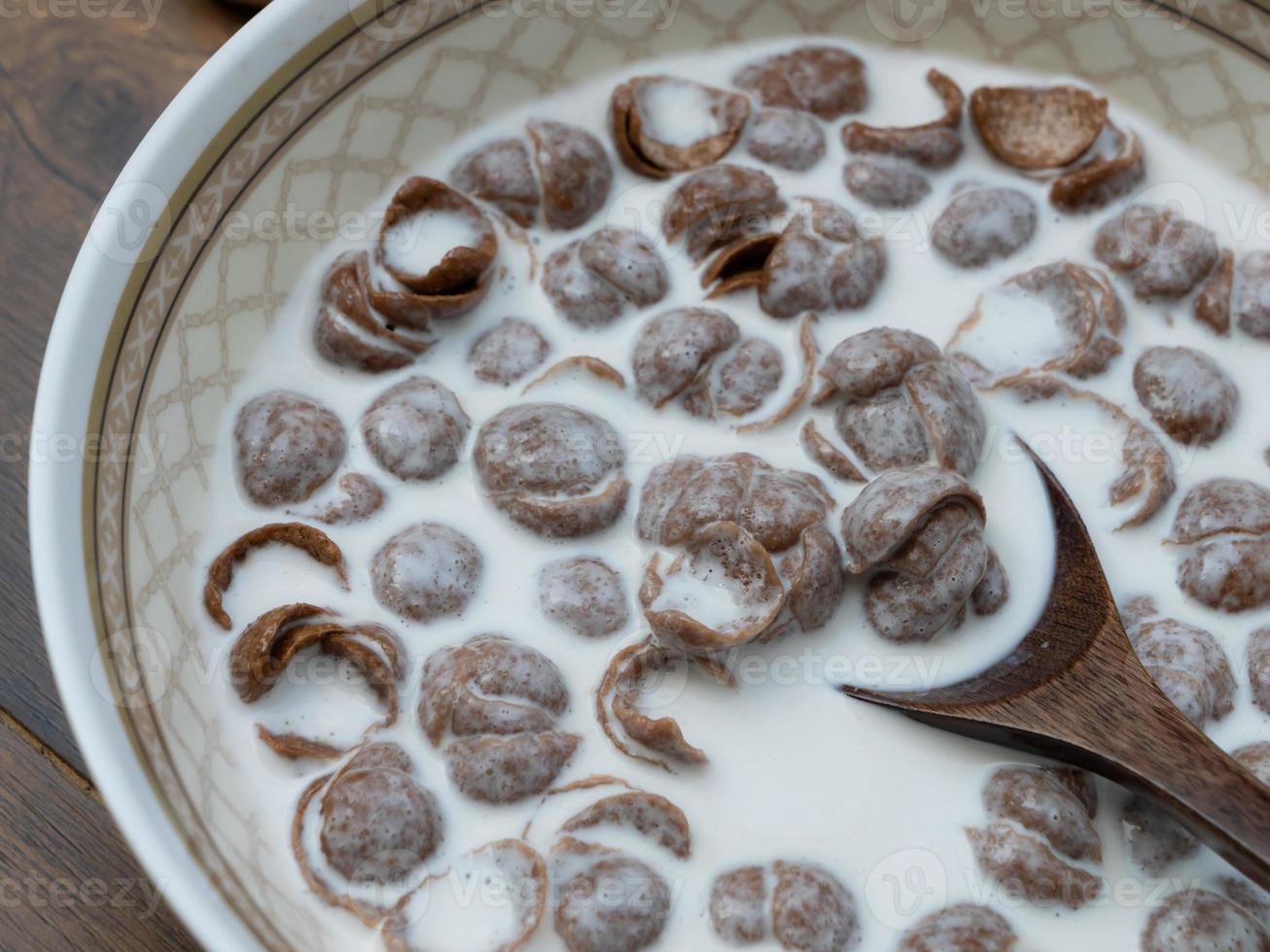 Close-up breakfast cereal topped with milk with a spoon and scoop to eat. photo