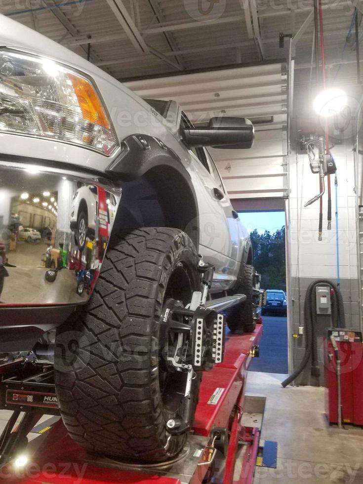 Closeup of tire clamped with aligner undergoing auto wheel alignment photo