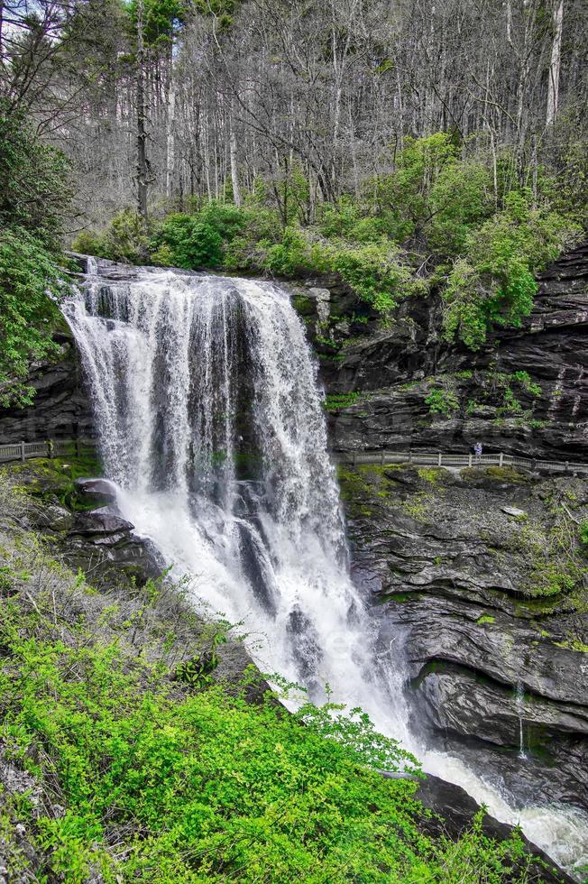A scenic waterfall roadside going over the cliff down to the boulders and rocks below where you can no longer drive under but can walk underneath the raging waters photo
