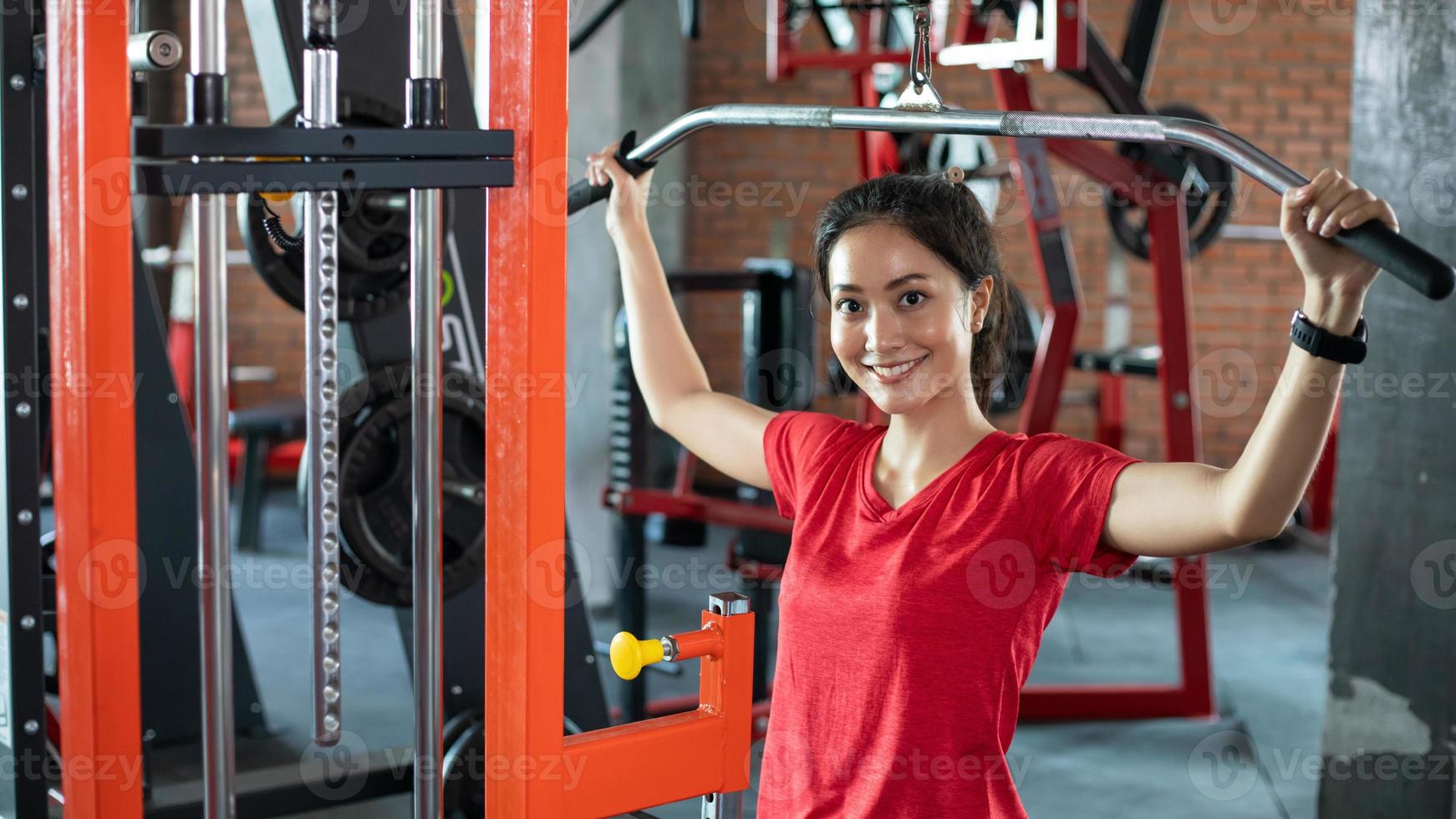 Athletic woman using machine for pumping back muscles in gym, front view  7568479 Stock Photo at Vecteezy