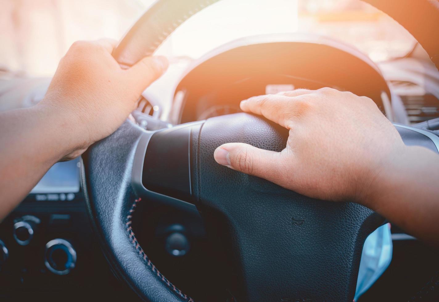 A man's hand is pressed to the horn of a car to warn vehicles that are not complying with traffic laws, which could pose a danger to his and other vehicles, as well as to the commuters photo