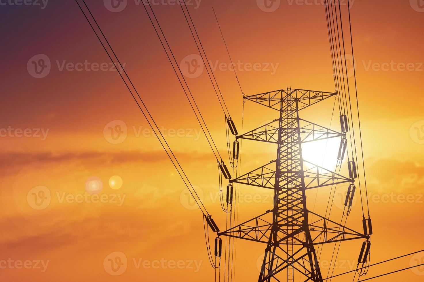 Silhouette of high voltage poles with electric wires. Silhouette of high voltage power line cables in an orange evening sunset. Steel structure of electric poles. electric power transmission concept photo