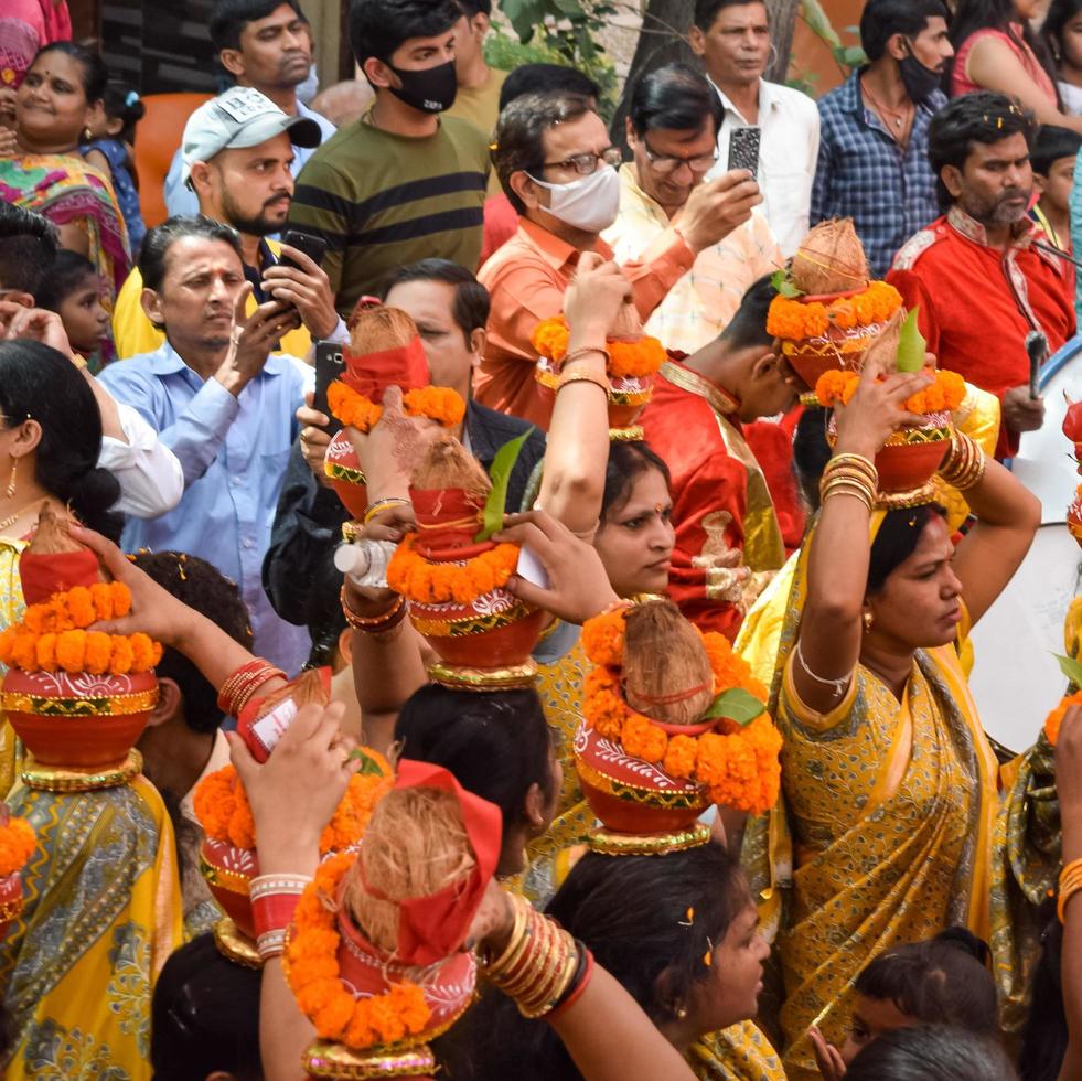 New Delhi, India April 03 2022 - Women with Kalash on head during Jagannath Temple Mangal Kalash Yatra, Indian Hindu devotees carry earthen pots containing sacred water with a coconut on top photo