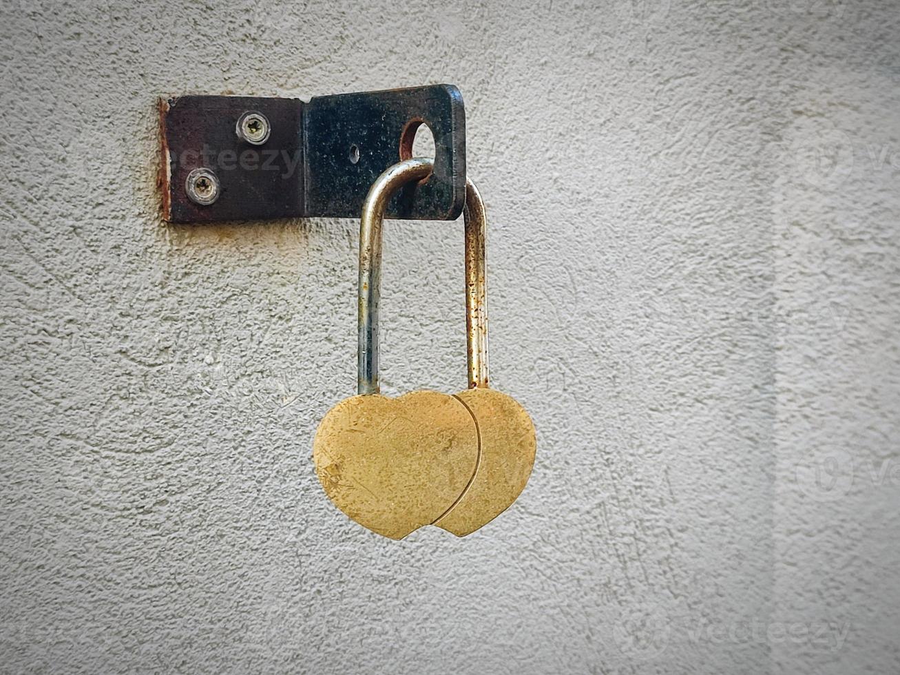 Two hearts padlock love symbol hanging on textured wall photo