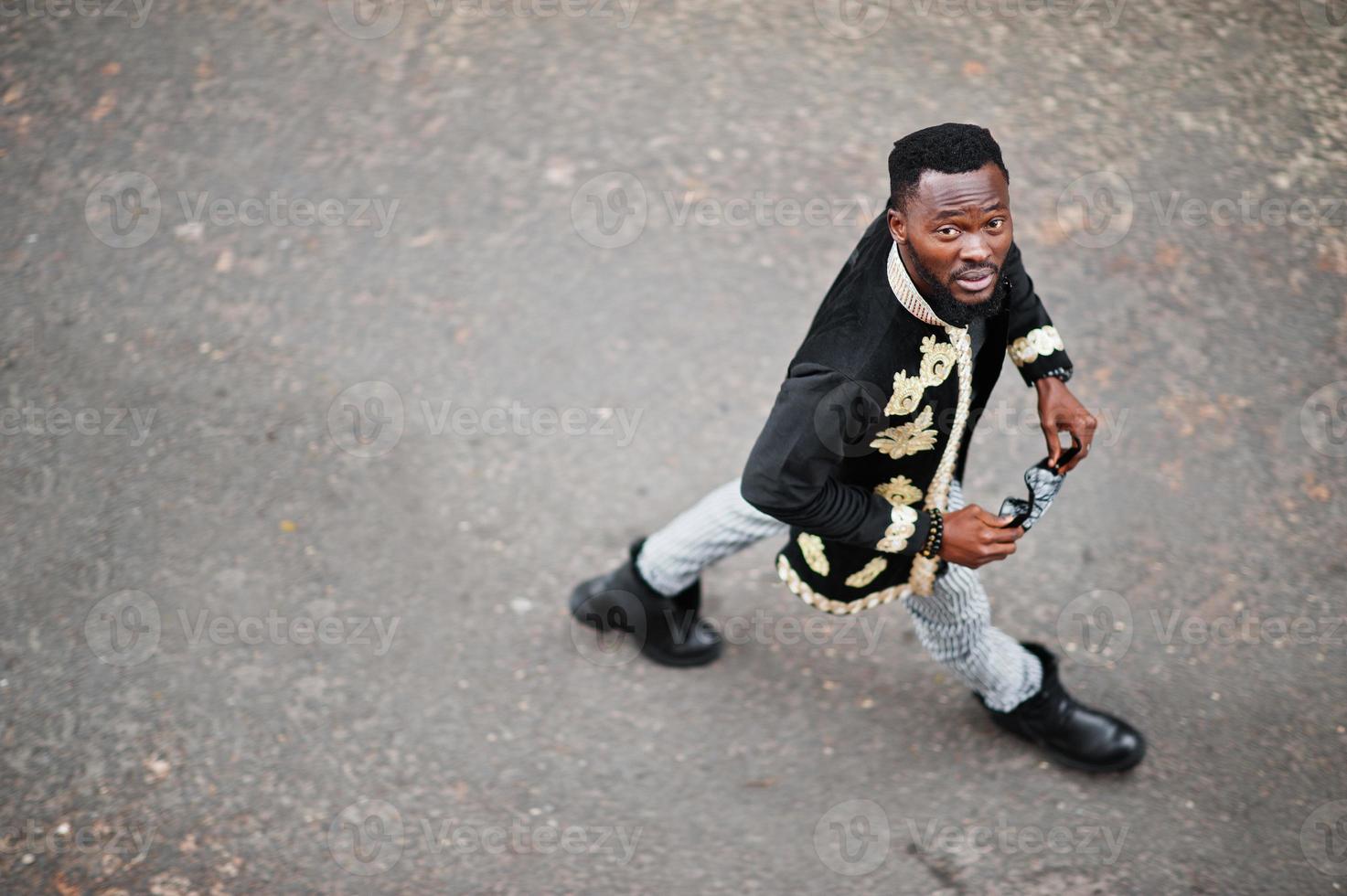 Mega stylish african man in traditional jacket pose. Fashionable black guy in sunglasses. photo