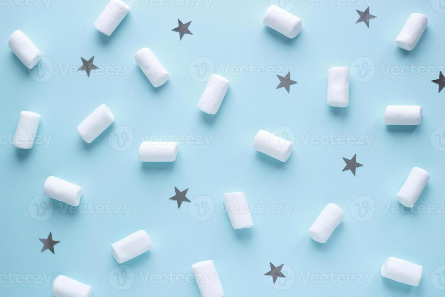 Geometric pattern of white marshmallows and stars on blue pastel background. Food concept in minimal flatlay style photo