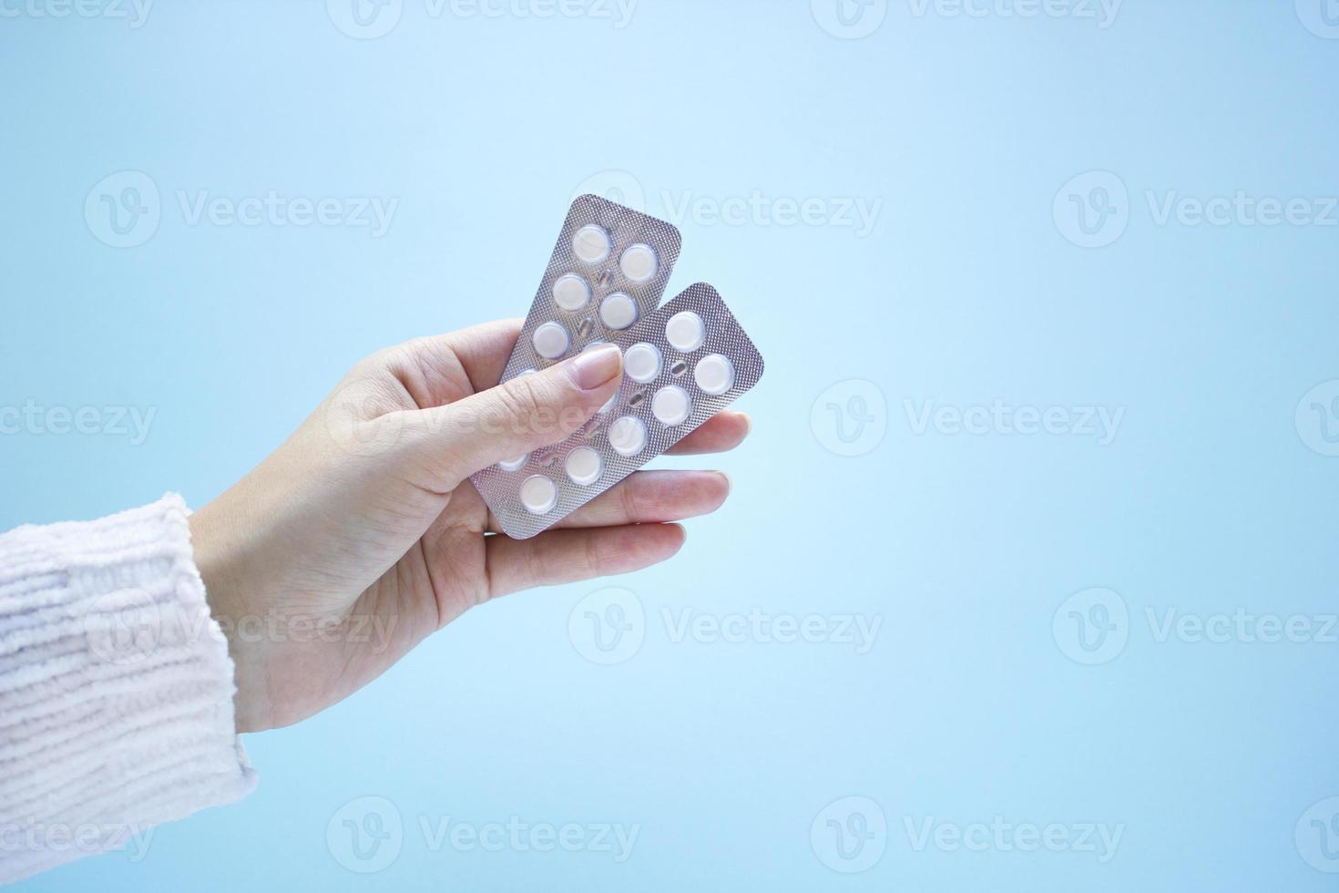 Woman hand holds two packs of tablets on blue background. Healthcare and medical concept with copy space. Treatment of diseases, sale of tablets, tablets in blister pack. Top view photo