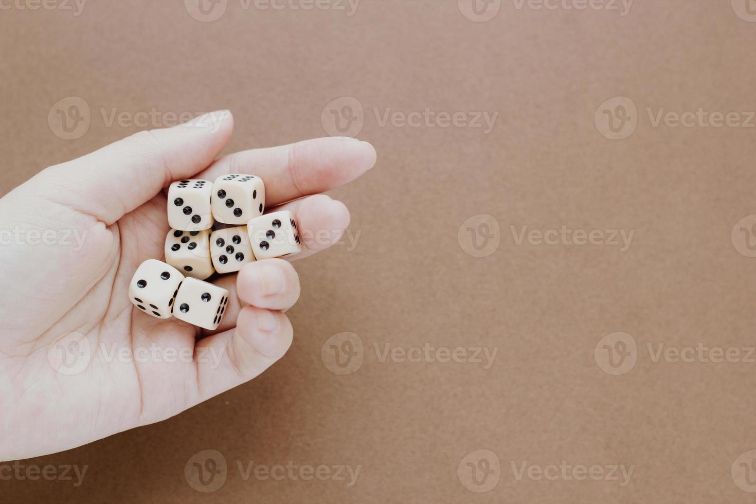 Female hand holds white gaming dice on brown background. Concept with copy space for games, game board, role playing game, risk, chance, good luck or gambling. Toned image top view. Close-up photo