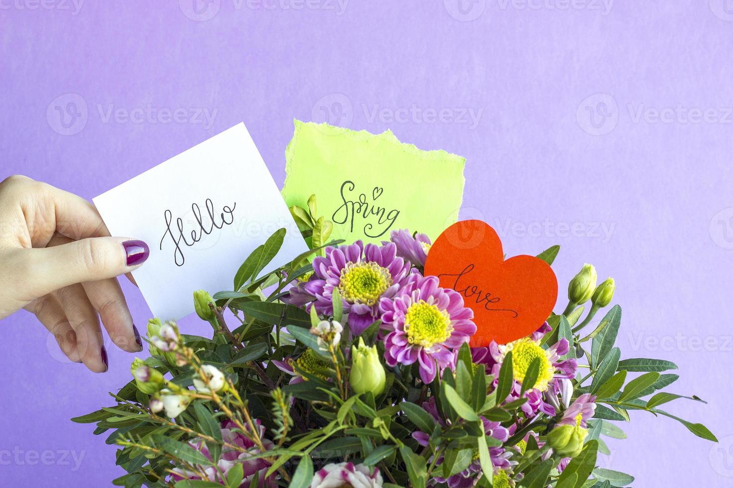 Floral composition with hand holding word HELLO, SPRING and LOVE on pink pastel background. Beautiful bouquet of spring flowers with copy space. Valentine Day, Mothers day, birthday, spring concept photo