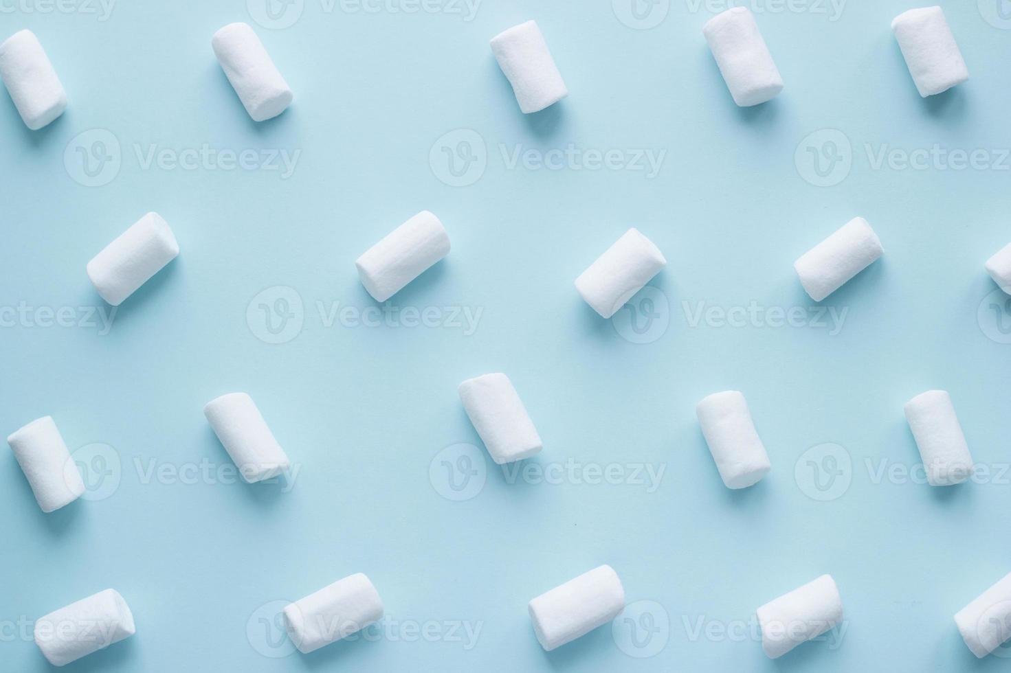 Geometric pattern of white marshmallows on blue pastel background. Food concept in minimal flatlay style photo