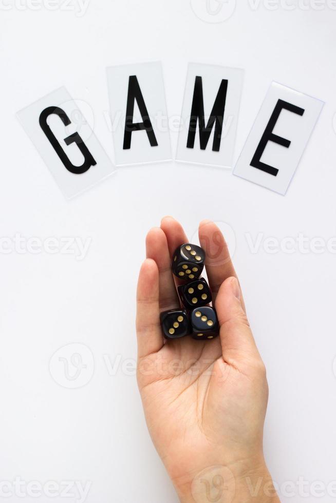 Female hand holds gaming dice on white background. Concept with GAME text for presentation, banners, game board, role playing game, risk, chance, good luck. Top view image. Close-up. photo