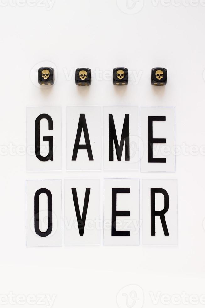 GAME OVER text and gaming dice with image skull on white background. Concept for banners, web pages, games, presentation. Top view photo