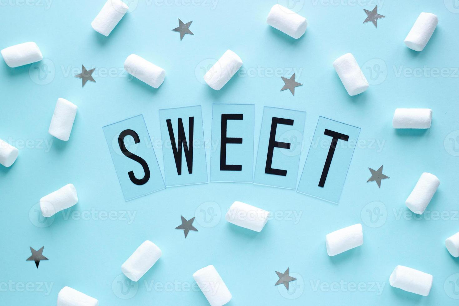 White marshmallows and stars with SWEET word on blue pastel background. Food concept in minimal flatlay style. Horizontal image top view photo