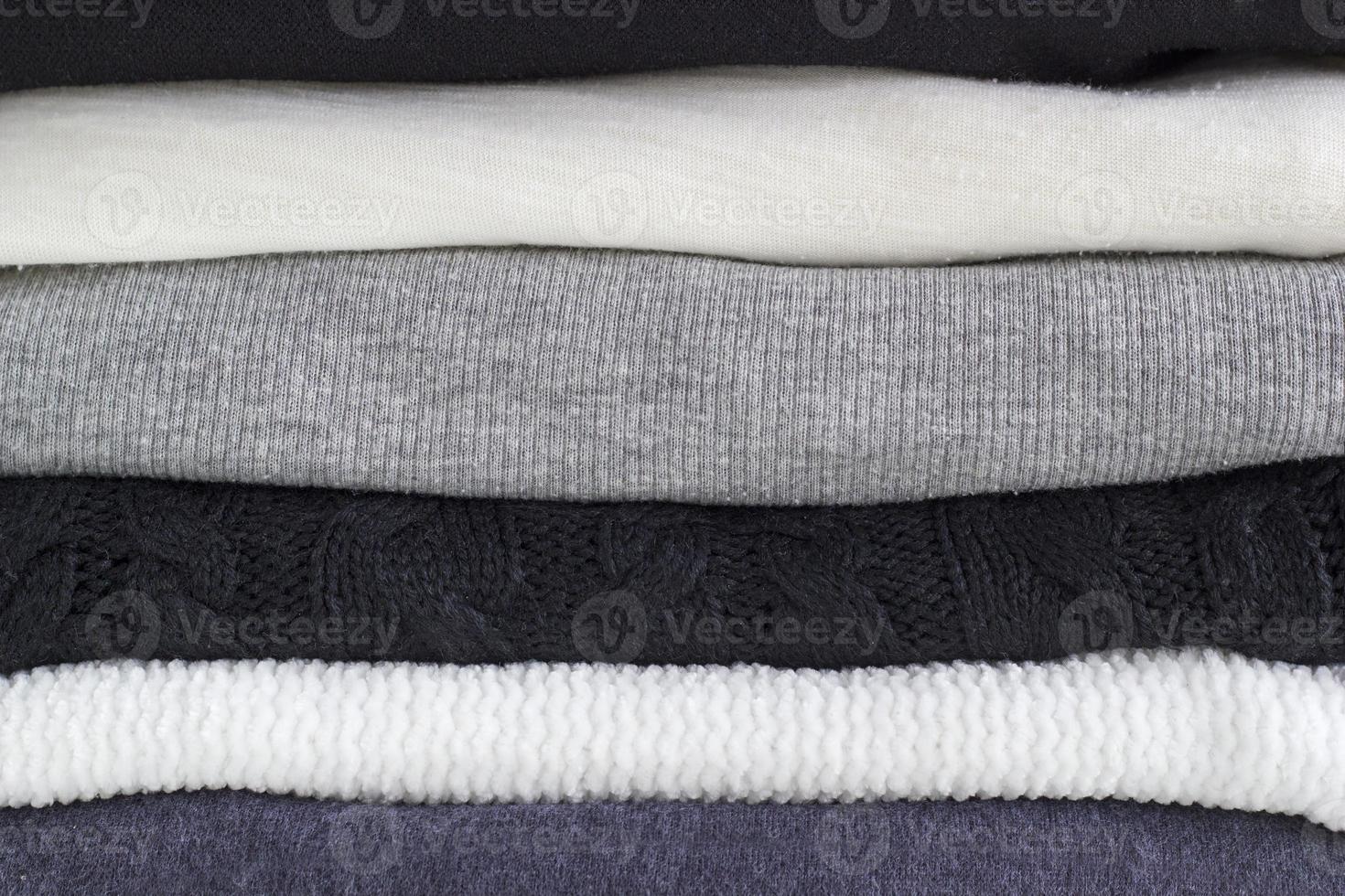 Close-up stack of folded cozy clothes. Black, grey and white textiles clothing. Monochrome fabric. photo