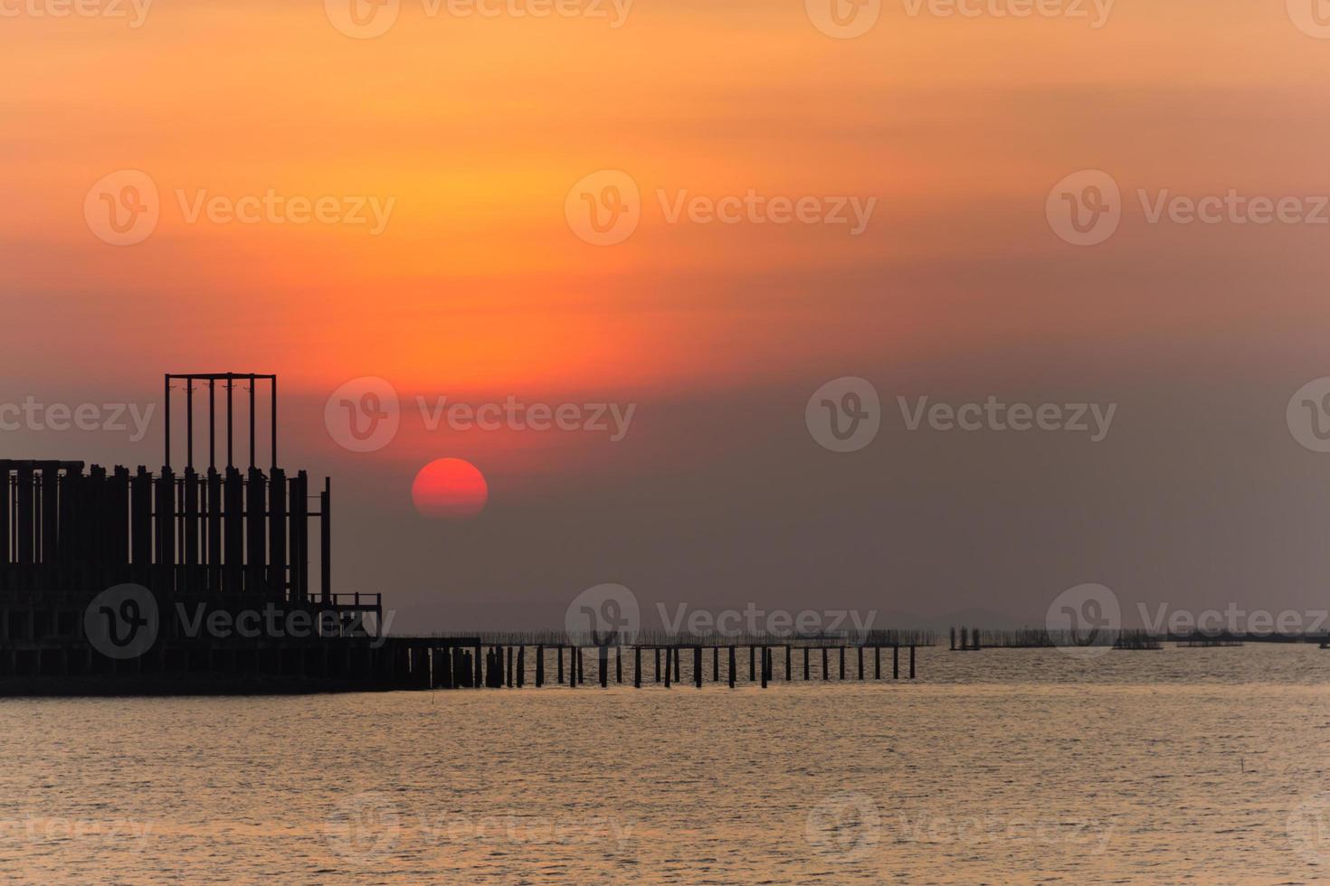Sunset on the beach, Foreground are buildings and fish cages. photo