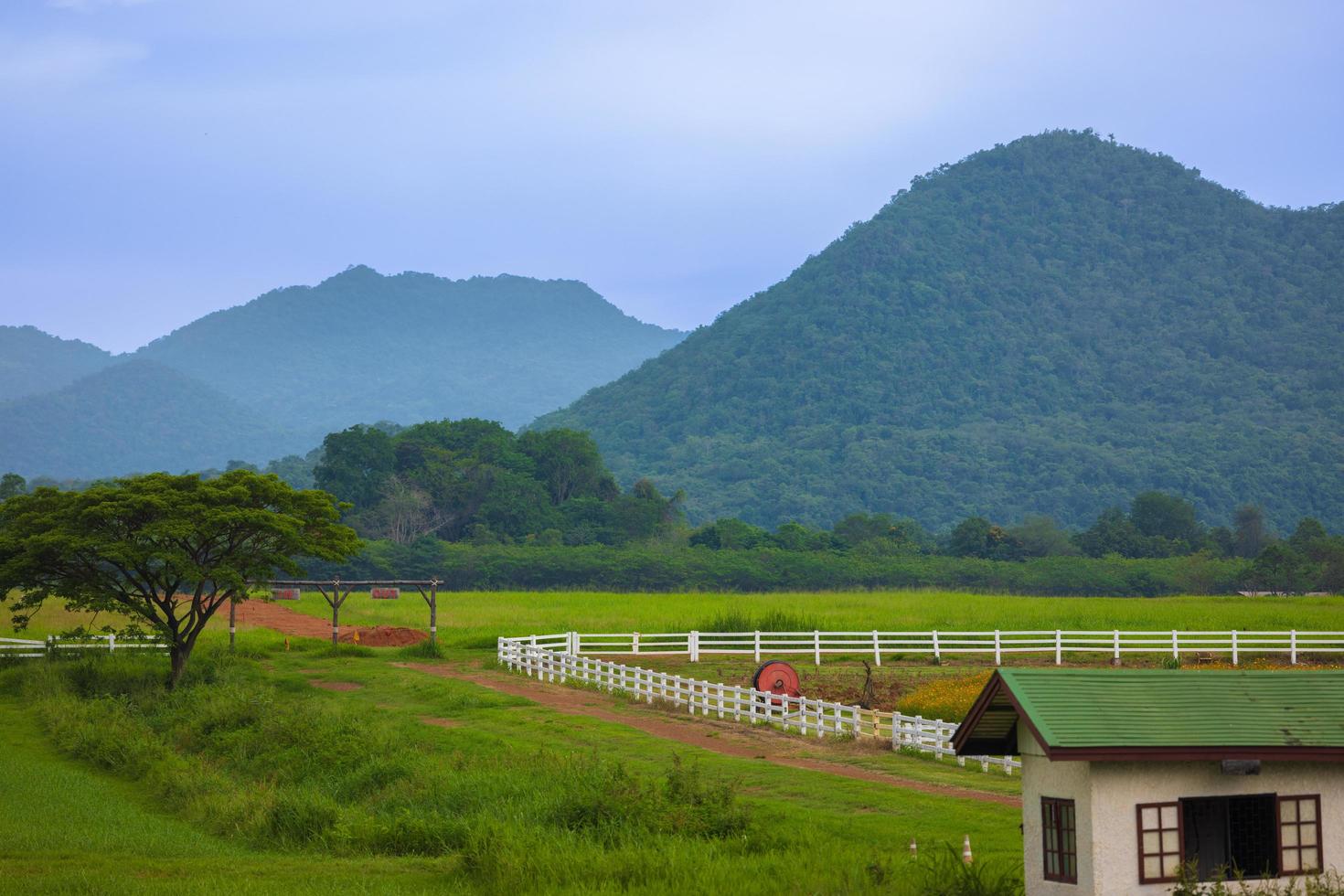 The green ranch behind the mountain has a bright blue sky. photo