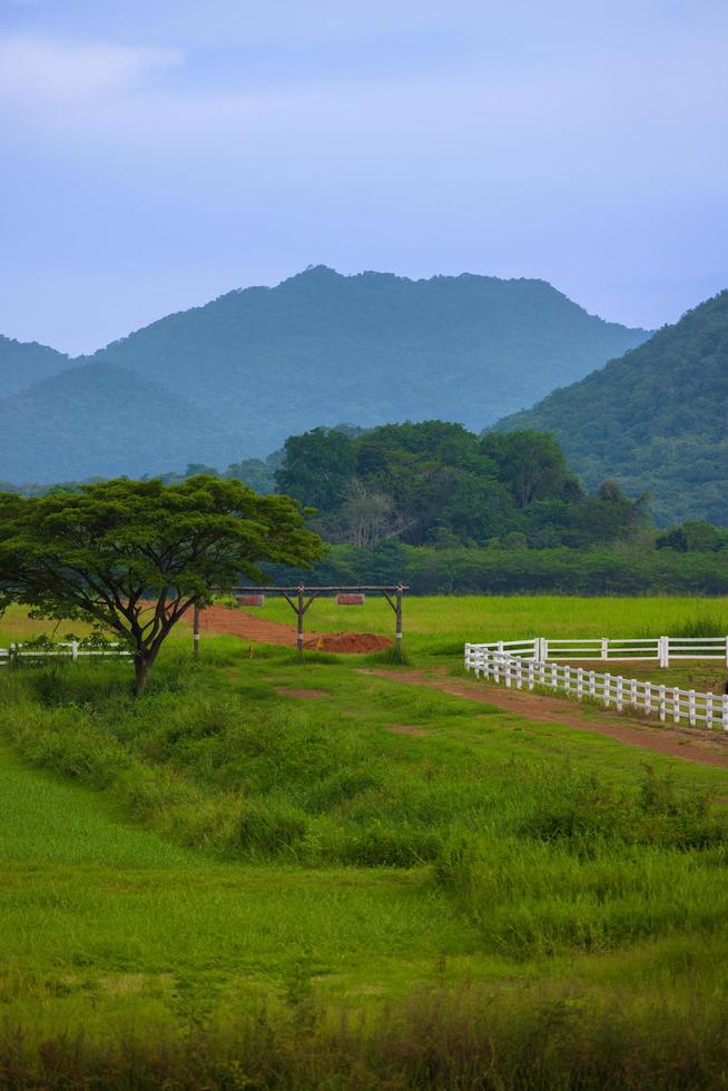 The green ranch behind the mountain has a bright blue sky. photo