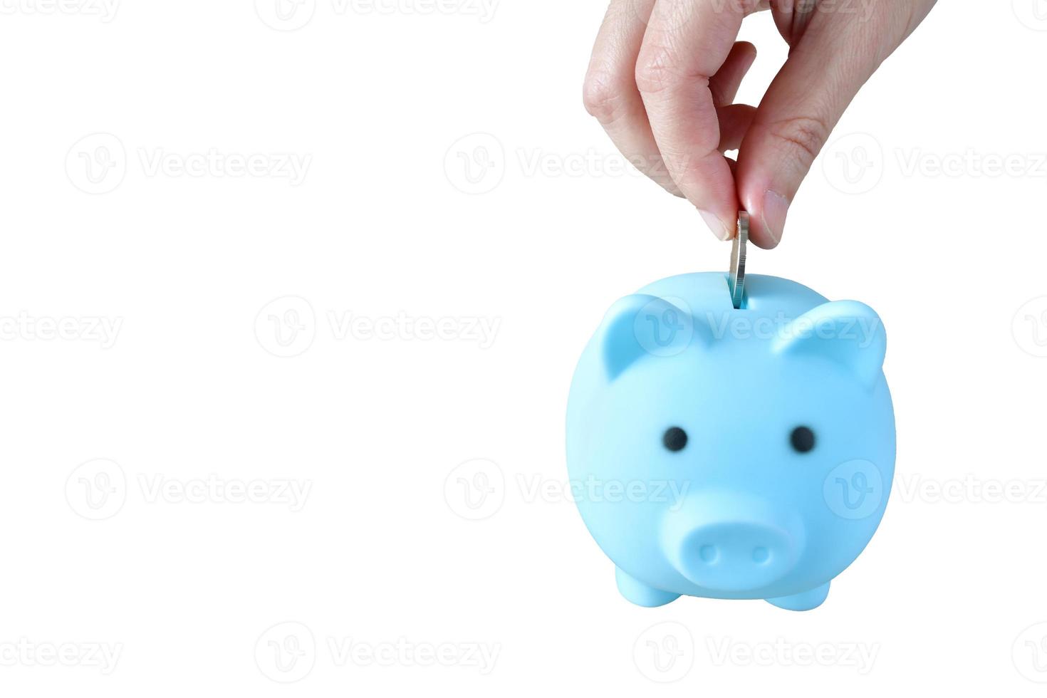 A woman puts a coin in a blue piggy bank on white background  to save money And record household income on the tablet with clipping path. photo
