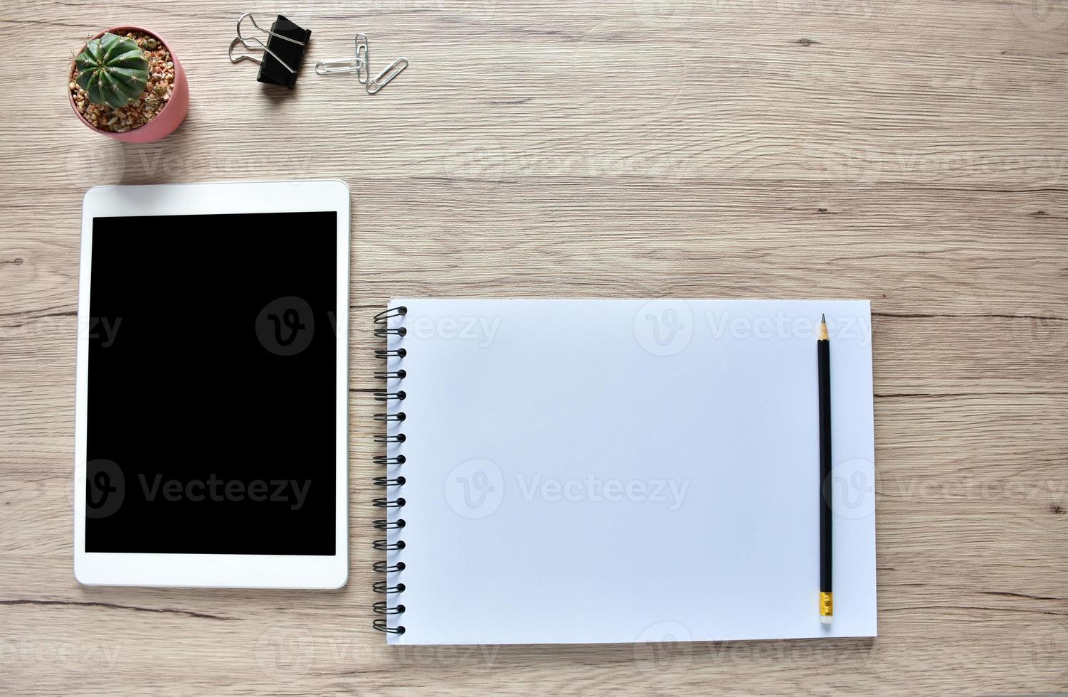 Work from home concept ,blank Tablet, office supplies, pencil, and Cactuspod  on wooden desk with copy space. photo