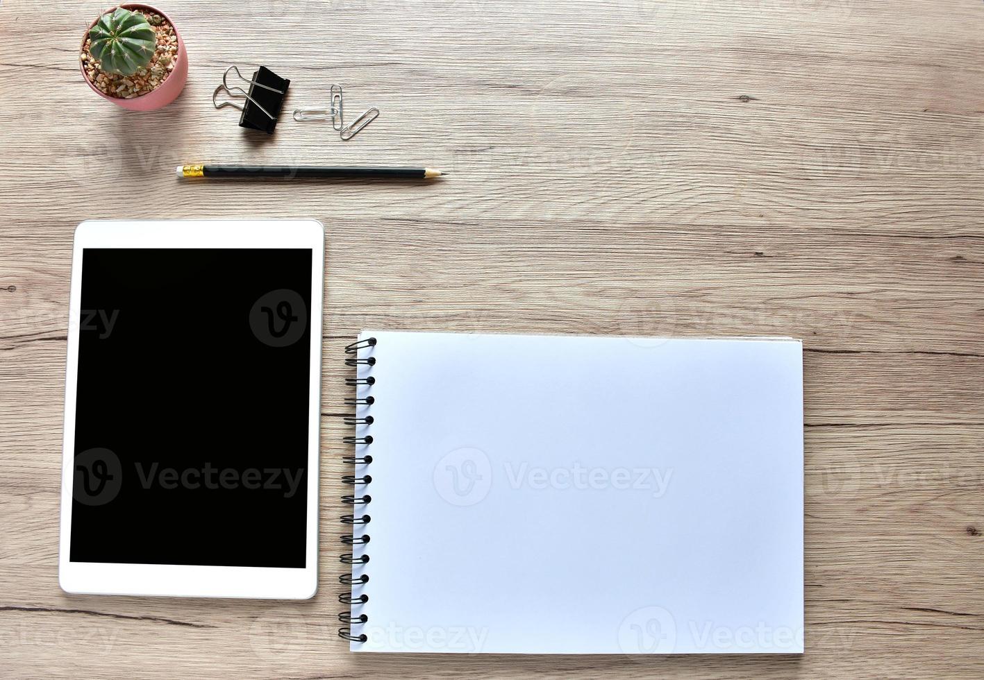 Work from home concept ,blank Tablet, office supplies, pencil, and Cactuspod  on wooden desk with copy space. photo