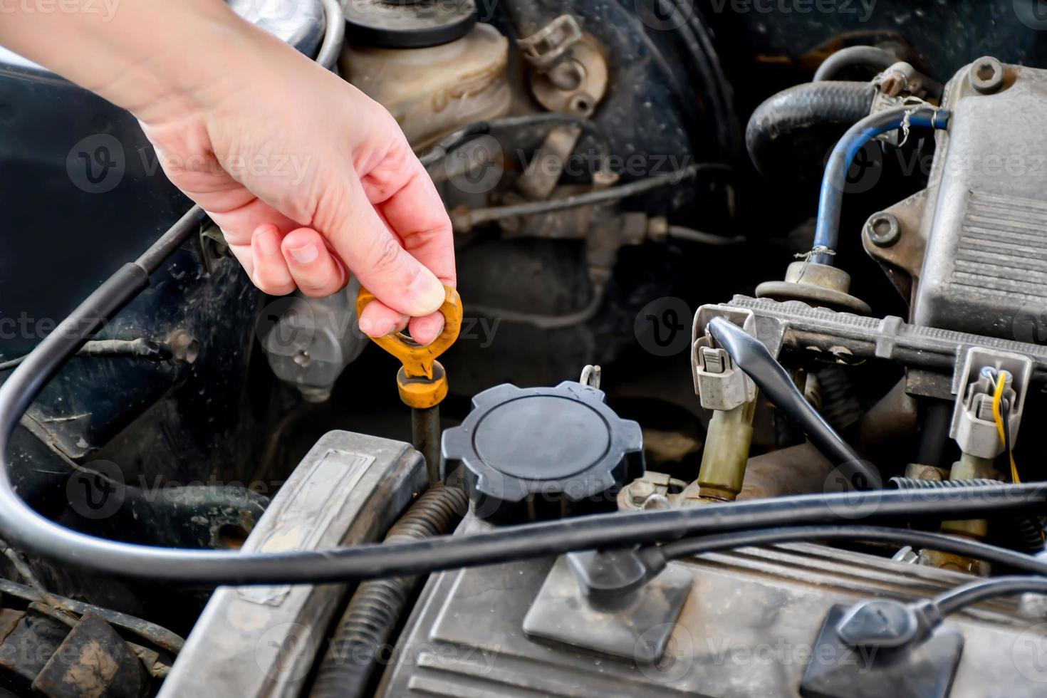 A woman checks the radiator of an old car parked in the garage to check the car before using it. photo