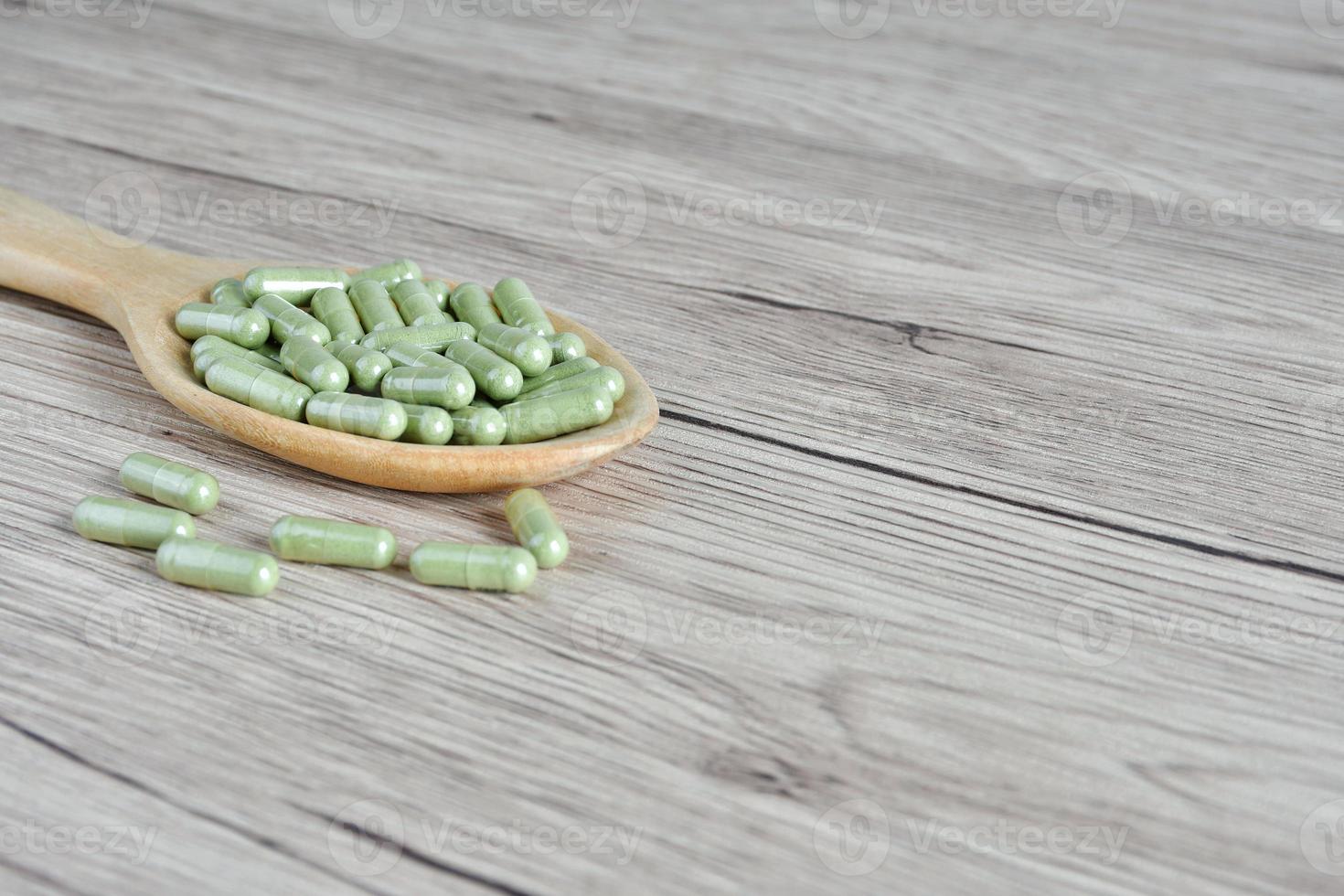 Thai herbal medicine name Andrographis paniculata is used to treat heat symptoms, reduce fever, relieve pain. Packed in capsules, placed on a wooden spoon photo
