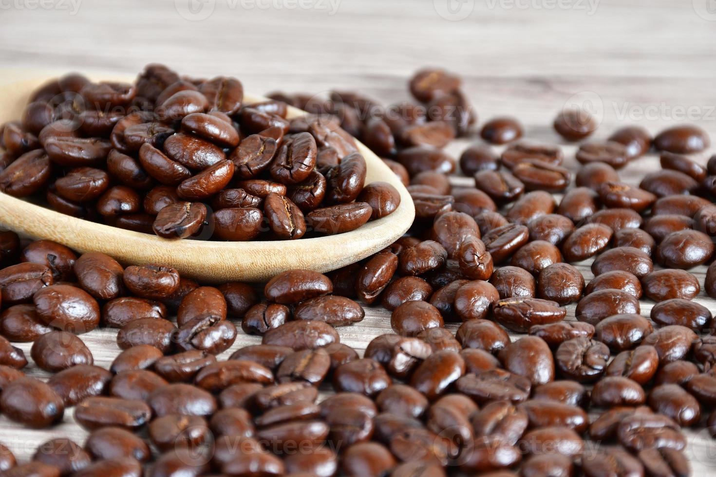 Close up Coffee beans in a wooden spoon on a table photo