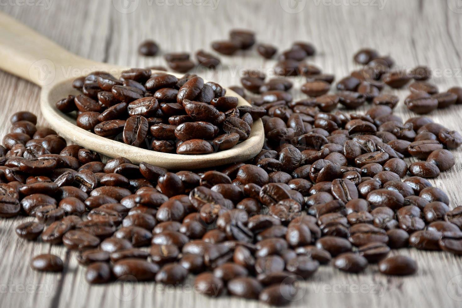 Close up Coffee beans in a wooden spoon on a table. photo