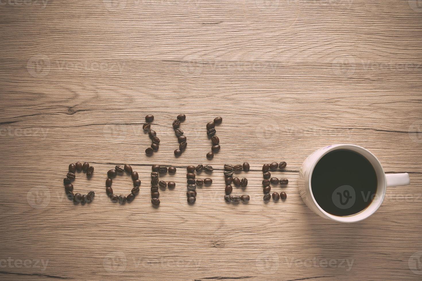 Top view Coffee beans are arranged in alphabetical terms, coffee and coffee cup laid on a wooden table. photo