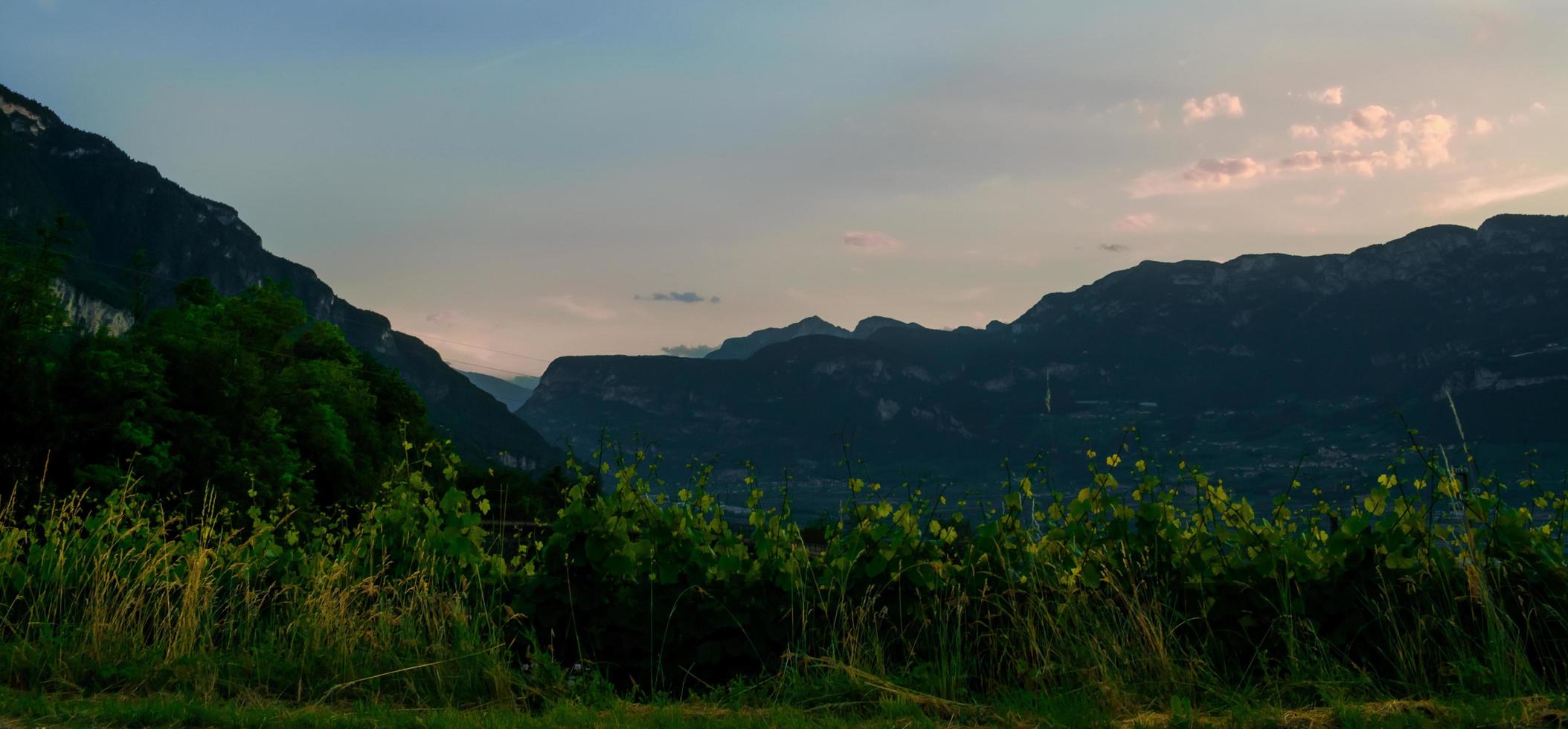 Sunset in the countryside with mountains in background, behind vineyards and lands, orange cloudy sky before night after sun settled down photo