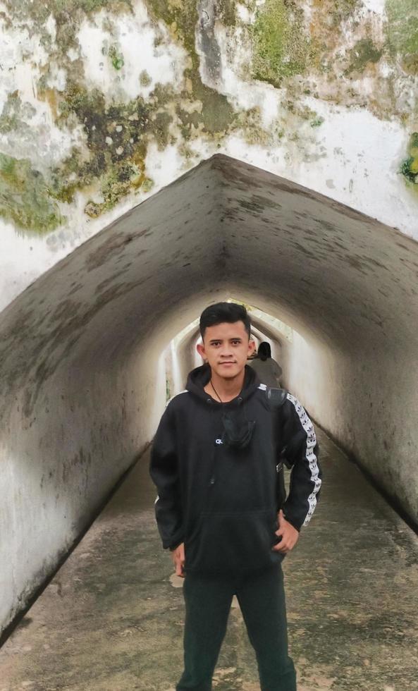 Sukoharjo - June 5, 2022 - young asian man dressed in all black standing in the middle of Taman Sari tunnel photo