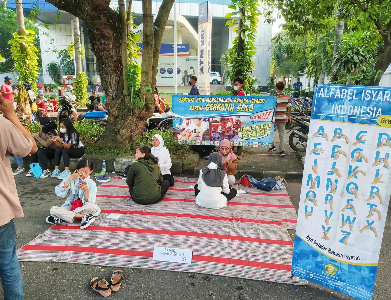 Sukoharjo - June 7, 2022 - people with disabilities sitting on mats teaching sign language to pedestrians photo