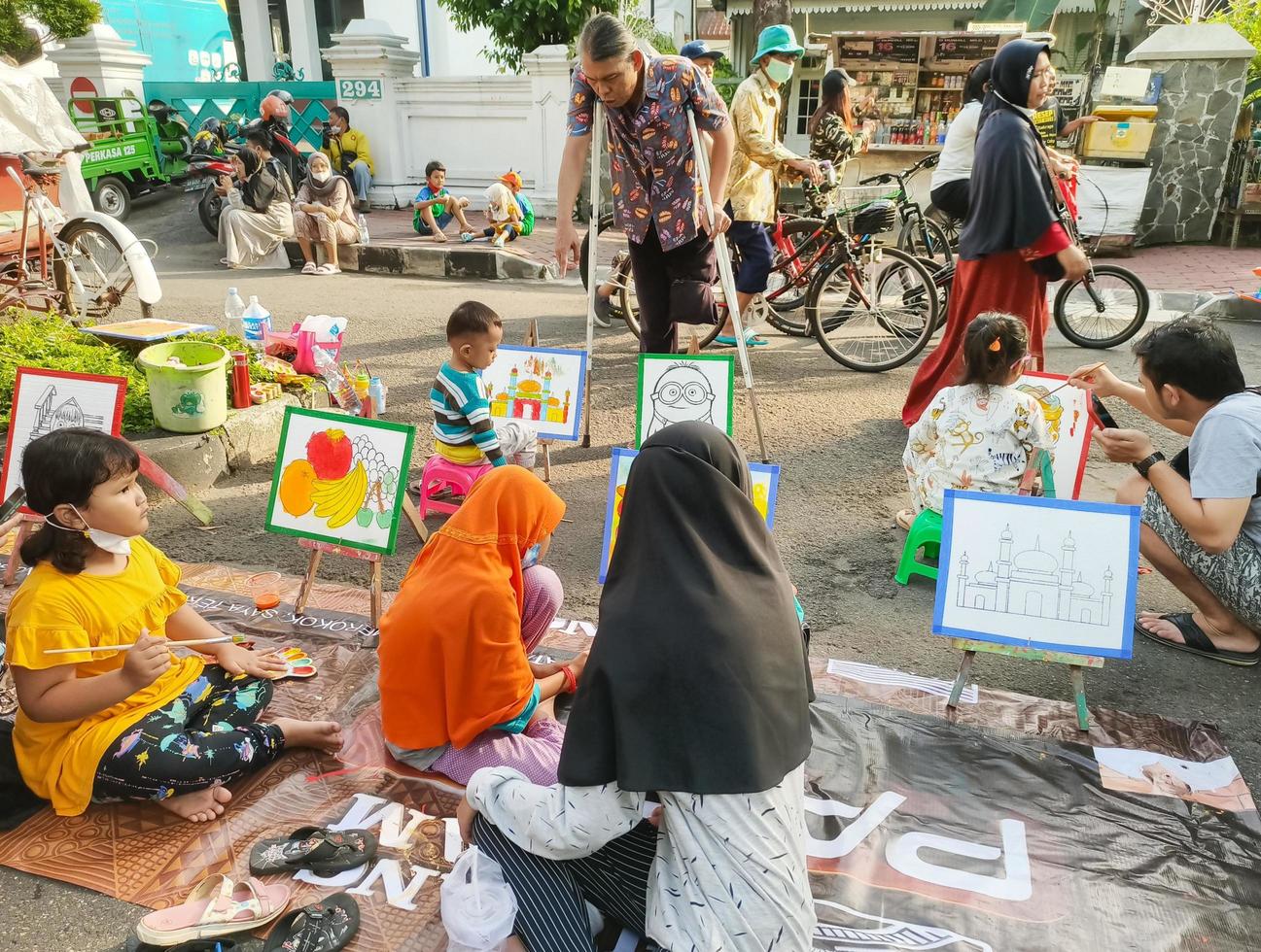 Sukoharjo - June 2, 2022 - an old man with a disability supervises and directs small children to color the painting photo